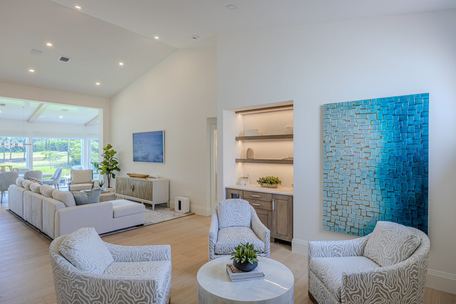 An open-concept living space with designated siting areas. The blue paintings on the walls help add a coastal feel to a modern space.